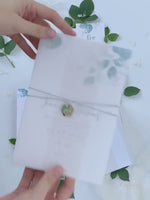 Hochzeiteinladung im Pergamentumschlag im Eukalyptus-Design mit sechseckigem Anhänger
